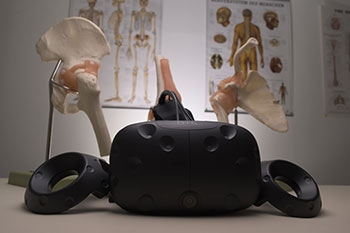 A VR headset with anatomy posters and bone samples in background