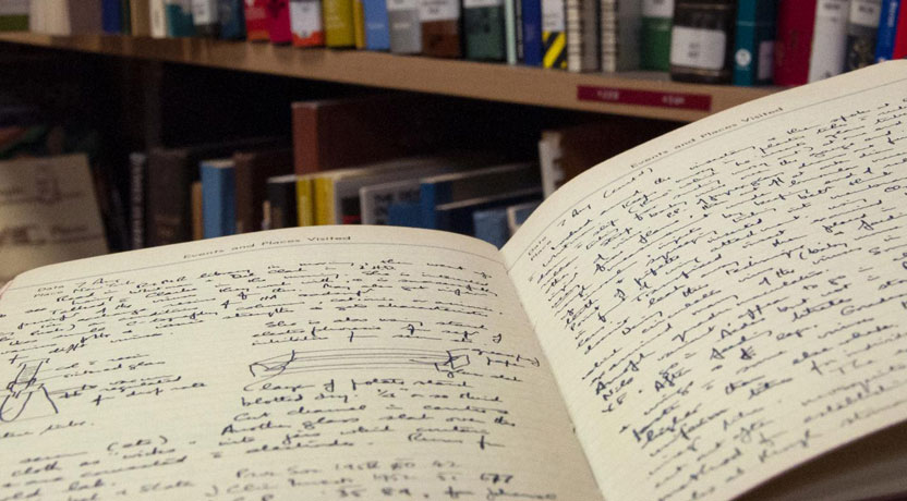 Open pages in an old handwritten notebook, in a library setting