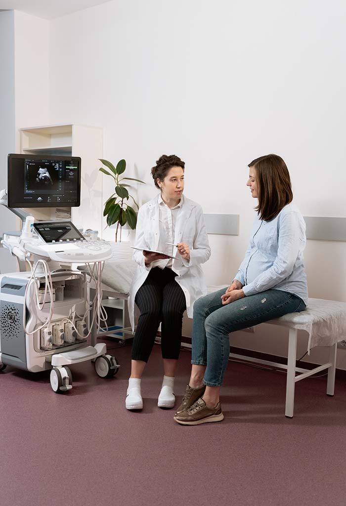 : A doctor and patient discuss a sonogram, which is visible on a screen in the room
