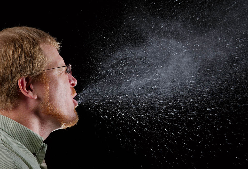 A person sneezing, showing a dramatic spray of saliva droplets