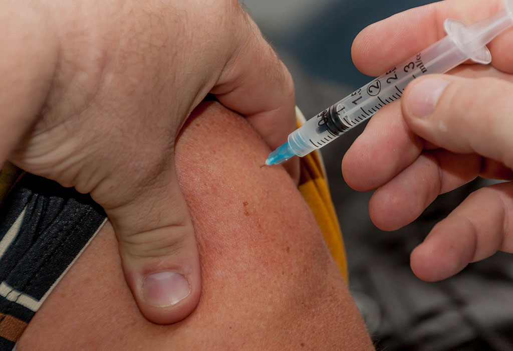 A vaccination needle injecting an inoculation into an arm