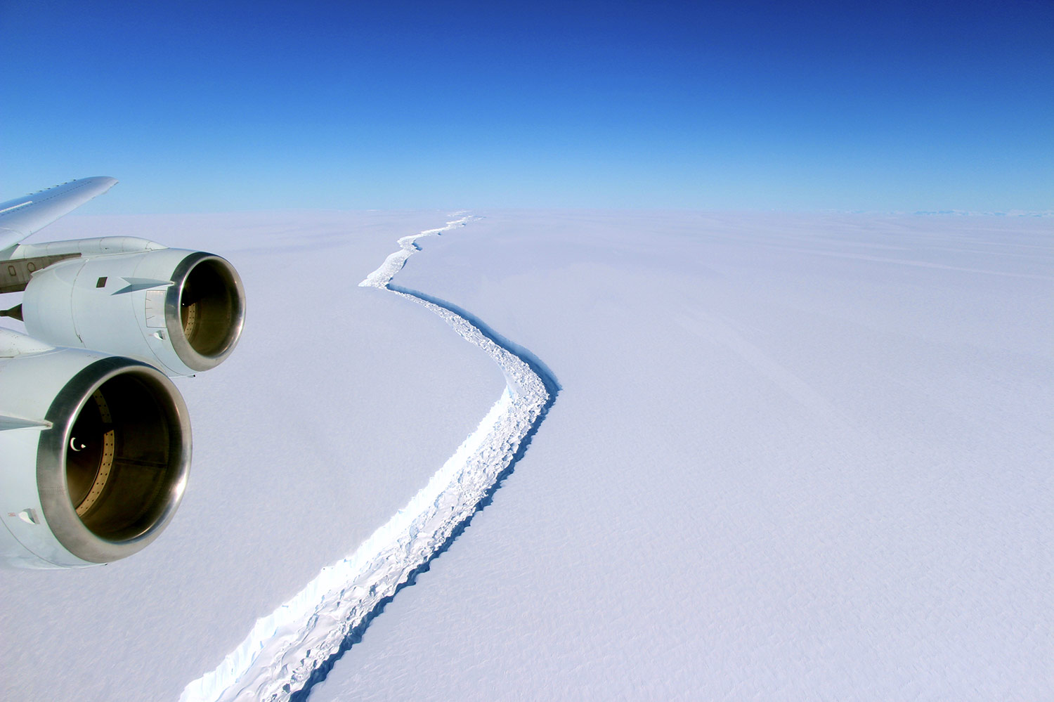 a wide crack on a large sheet of ice taken from through an aircraft window