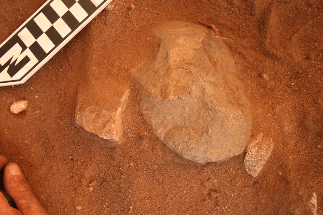 A stone tool half excavated from the soil