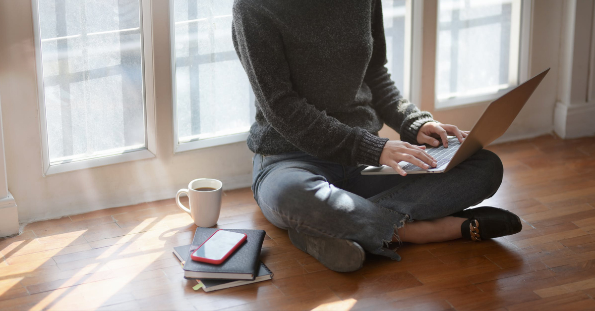  Person inside near window sits on floor with laptop.