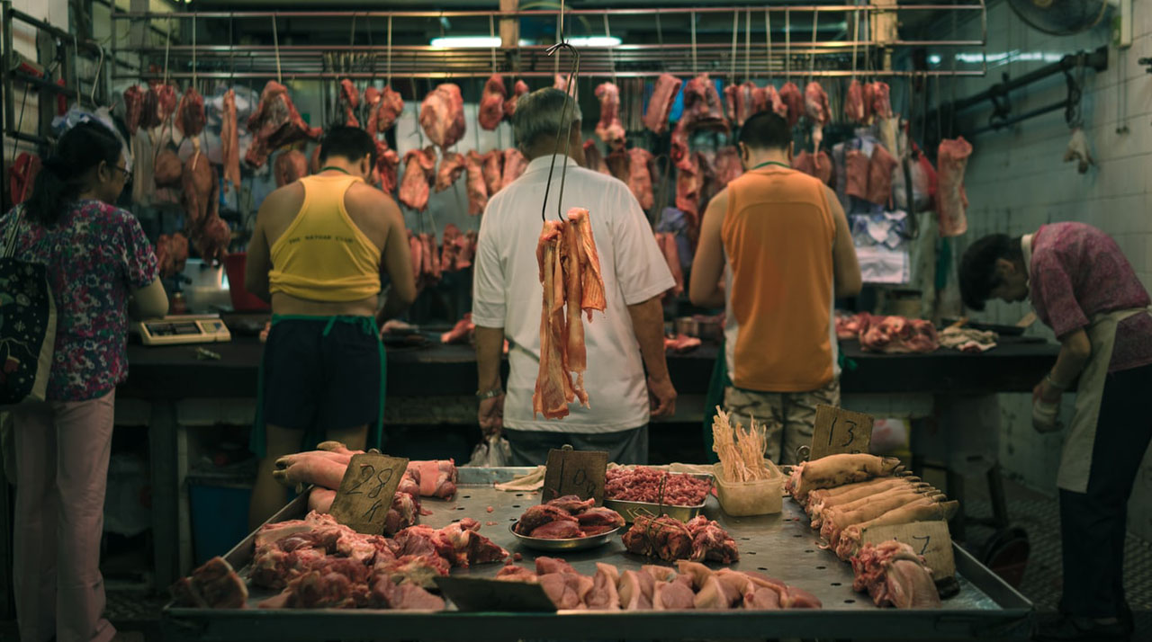 People working in an open market to butcher and sell meat