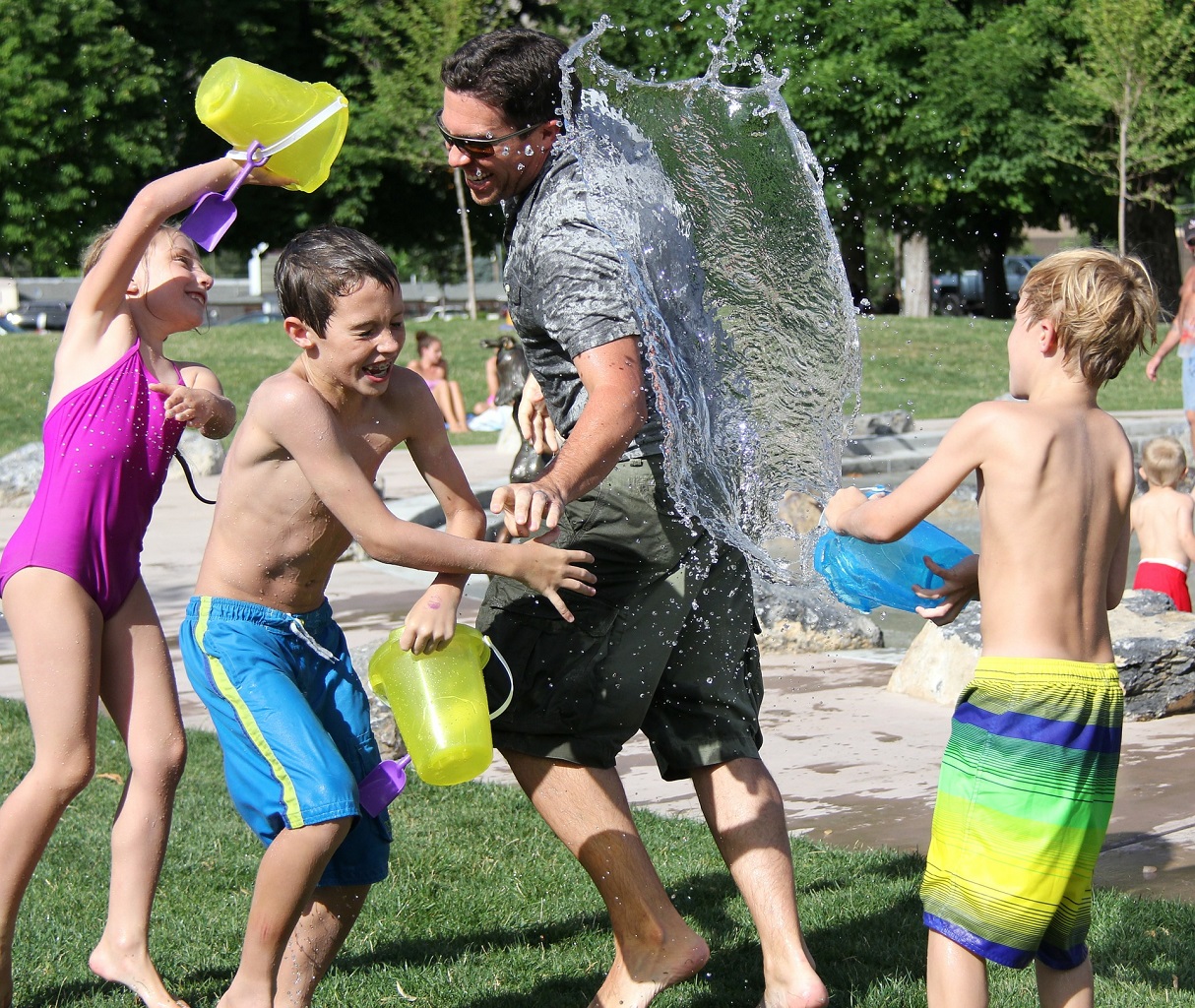 Adult and three kids playing with buckets of water