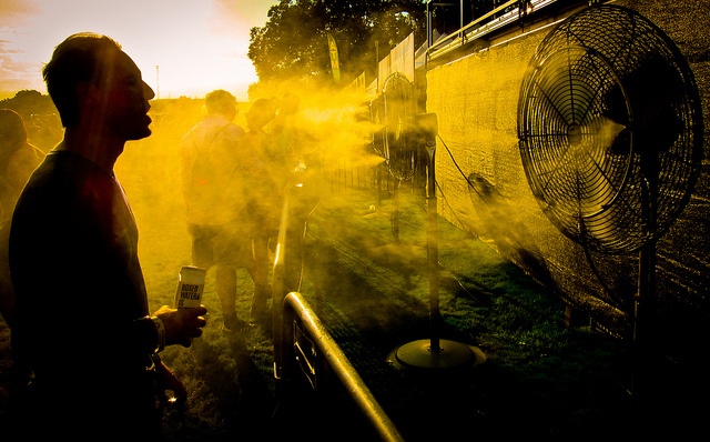 A man cools off in front of a fan.