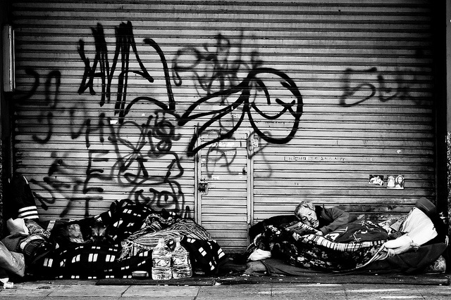 Homeless people in front of a garage door.