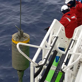 A photo of a core barrel being pulled up from the water.