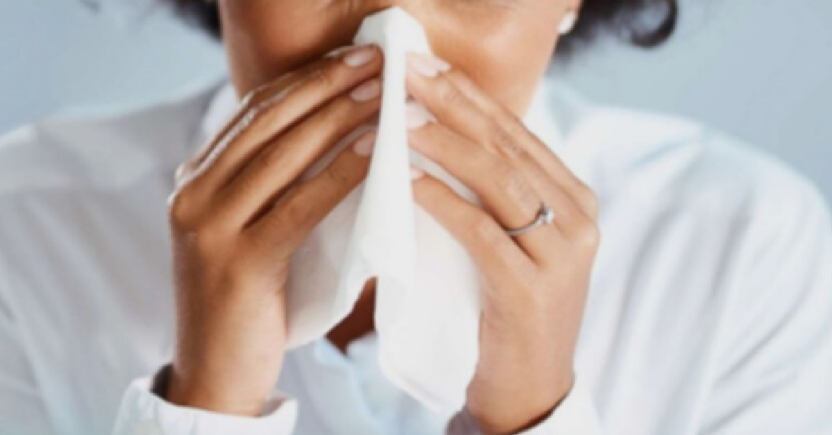  Woman sneezing into a tissue.