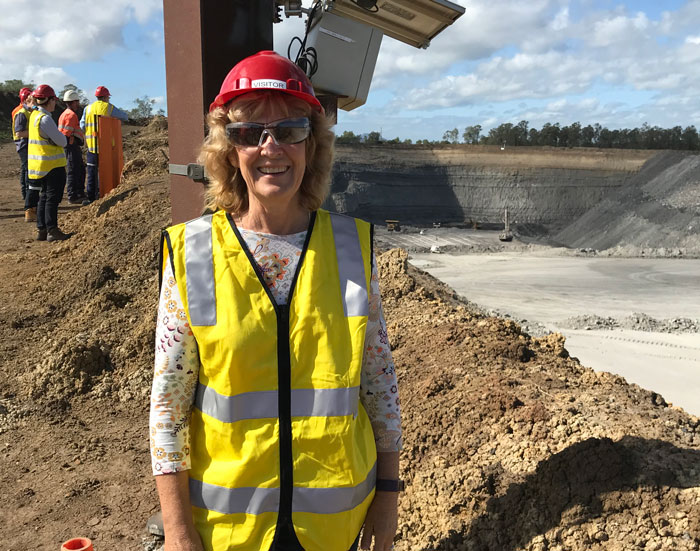 Dr Jenny Stauber in a hard hat and high visibility vest in front of a coal mine.