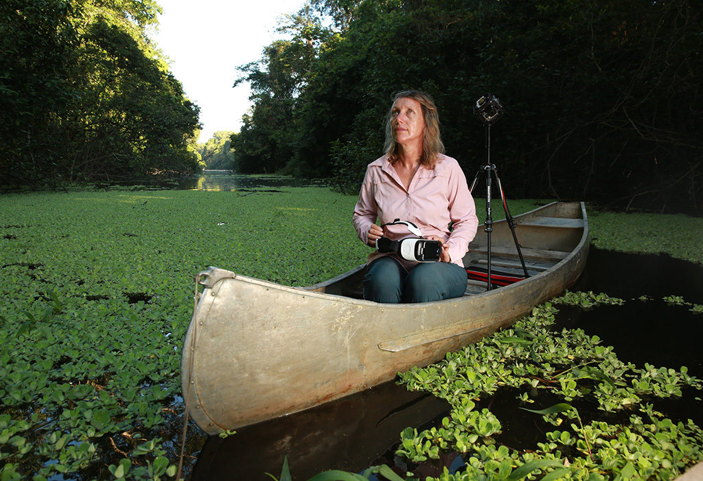 A person (Kerrie Mengersen) in a boat on a river with some VR equipment