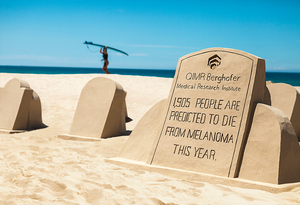 A sandcastle in the shape of a tombstone with the statistic: 1905 people are predicted to die from melanoma this year