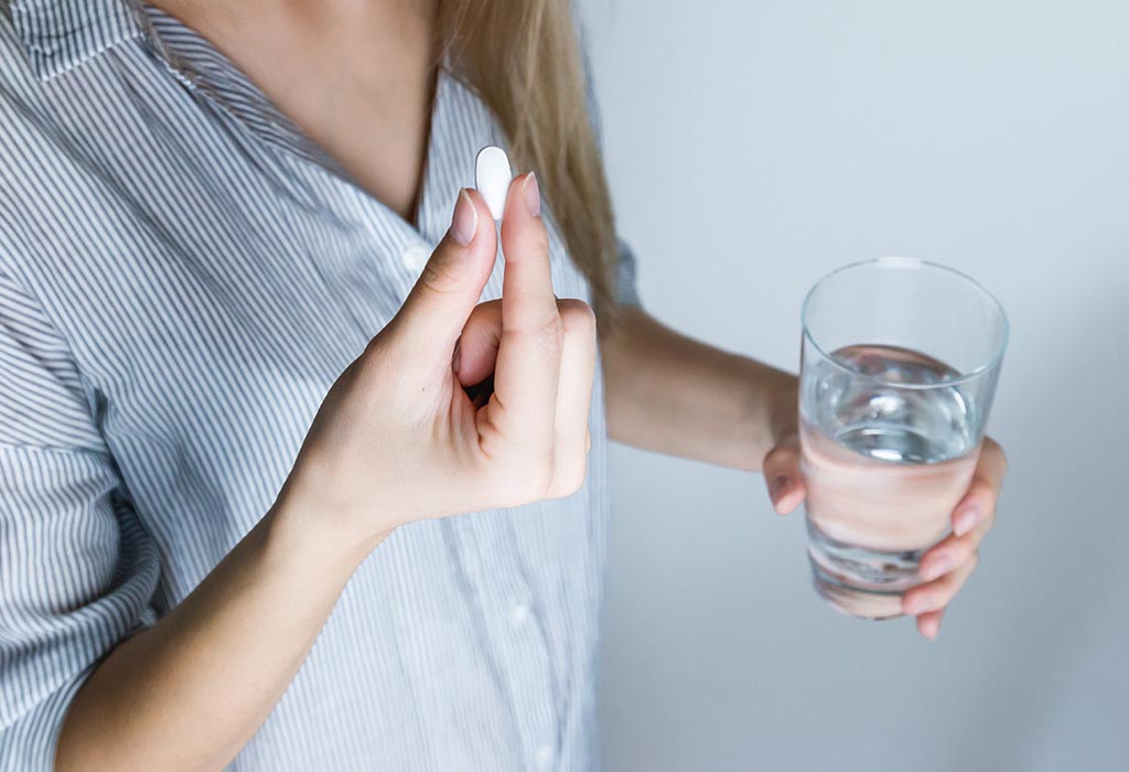 Someone holding a tablet and a glass of water