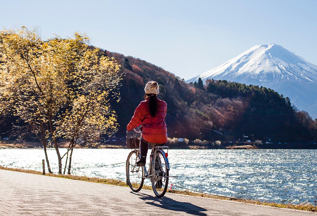 Someone riding a bike past a lake, with mountains in the background