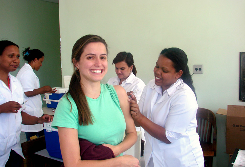 A group of people standing in a room, one of them is being vaccinated