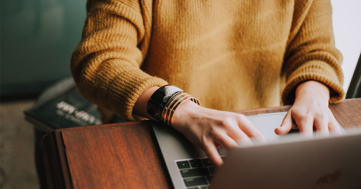 A person wearing a yellow jumper at a computer