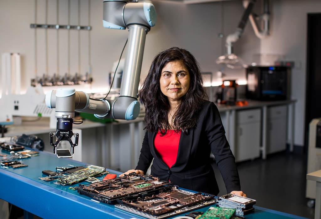 Prof Veena Sahajwalla standing in front of a table with electronic components on it