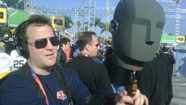 Man in a crowd holding up a head for recording 3D sound.