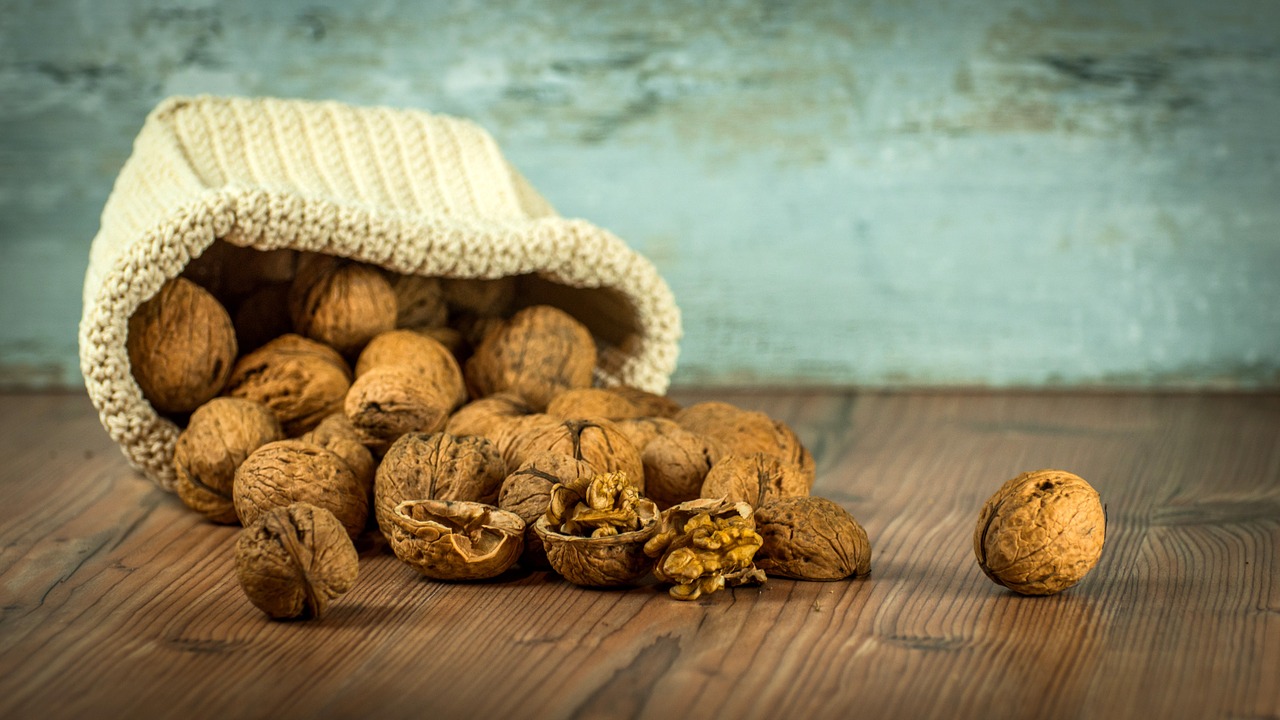 A bag of walnuts open and spilled on a table