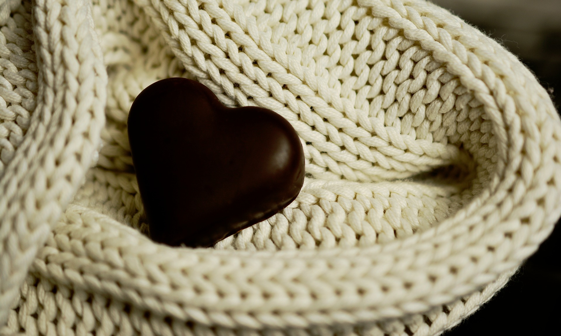 A heart-shaped chocolate on a knitted textile