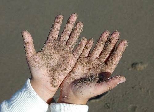 A pair of human hands covered in sand 