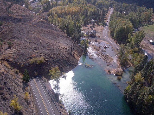 Aerial view of landslide burying a road and a damming a river 