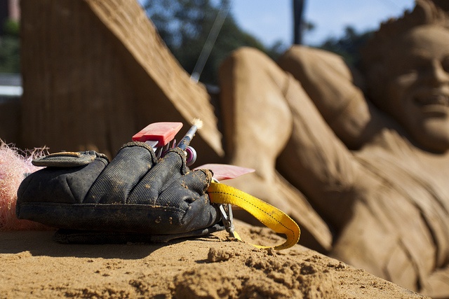 sculptor's tools with sand sculpture in the background 