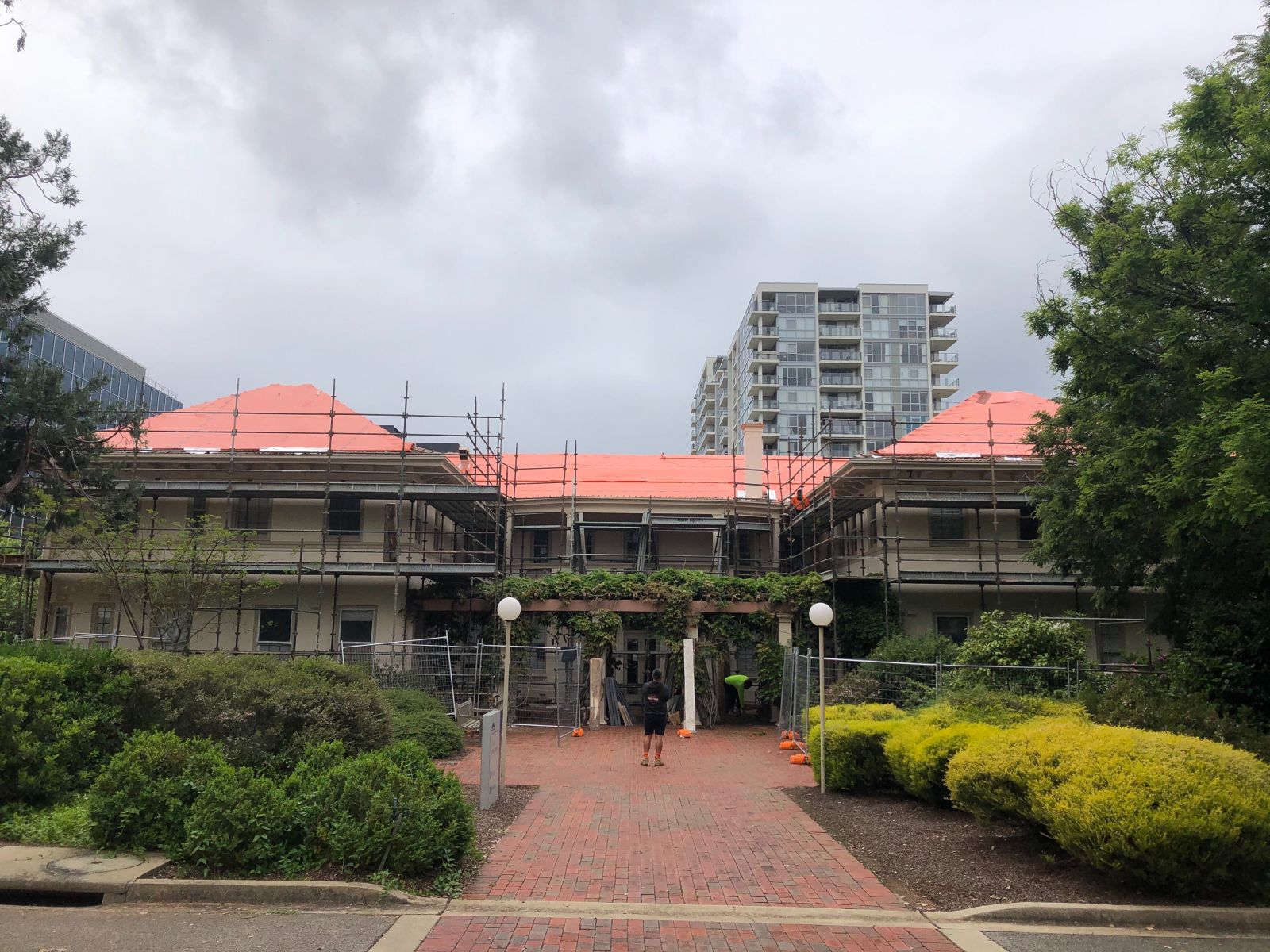 Roof covered in red plastic sheeting and building surrounded by scaffolding