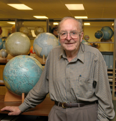 Ross Taylor standing in front of a collection of world globes