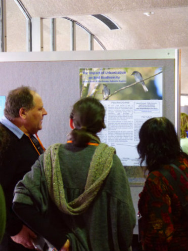 Three people looking at a poster pinned up on a board