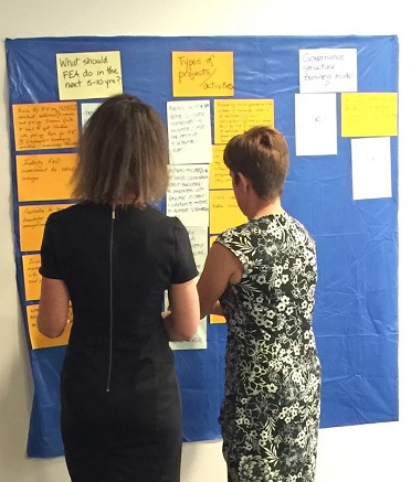 Two participants at the Future Earth workshop adding their ideas to a brainstorming pinboard