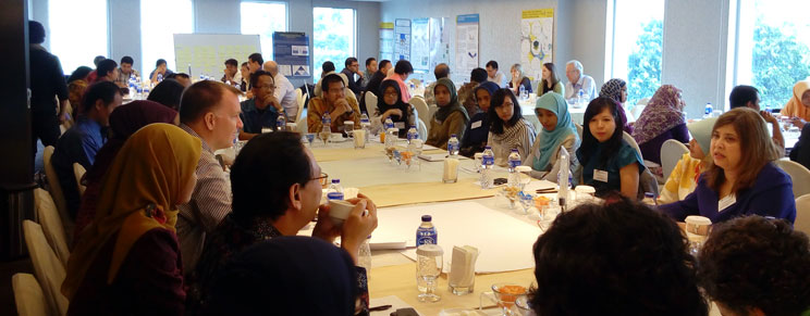 Large group of people in a room, grouped at tables