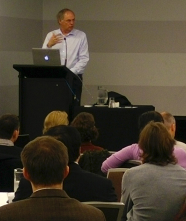 man presenting at a podium in front of an audience