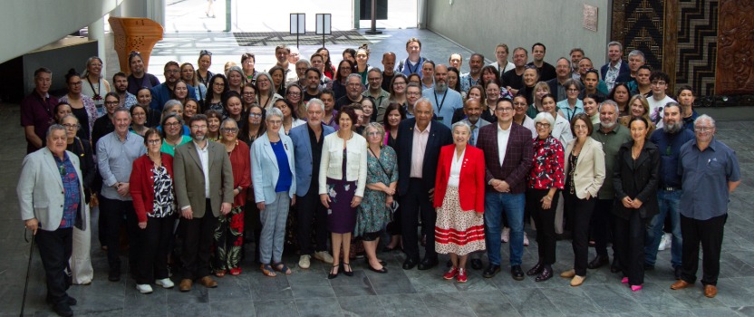 Large group of people stnding together in a building foyer.