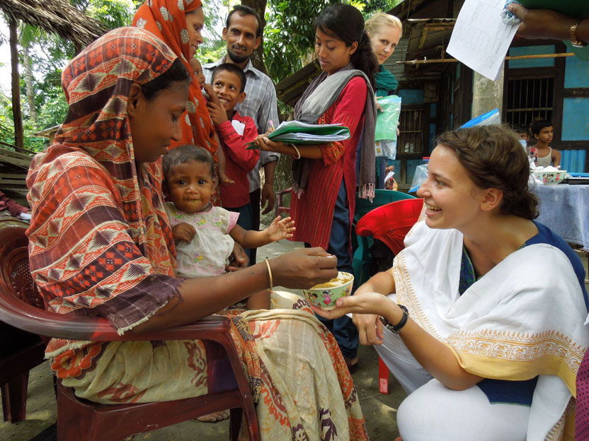 Woman helping a mother feed her young child