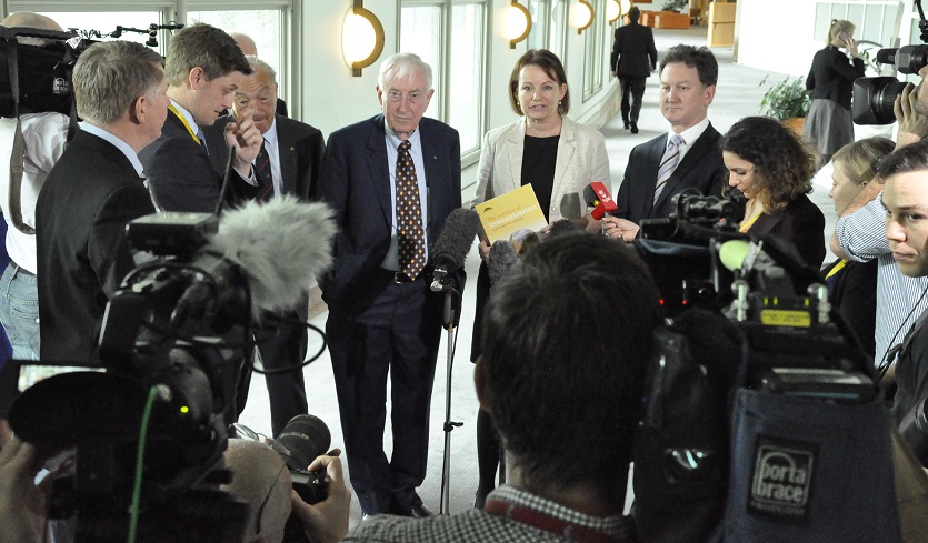 Minister for Health and others being interviewed in front of TV camera scrum