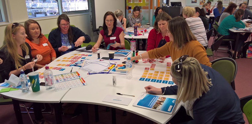 A group of smiling women around a table, working on activities