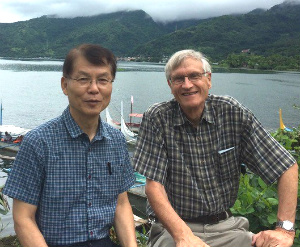 Two men smiliing, with lake and mountains in background