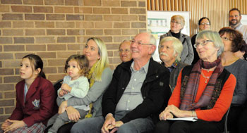 Denis Goodrum with others seated in the audience, including young children