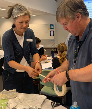 A male and a female adults working together to create something from tape and other simple materials