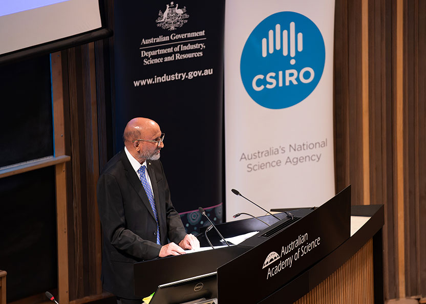 A man in a suit - Professor Chennupati Jagadish - stands behind a lectern