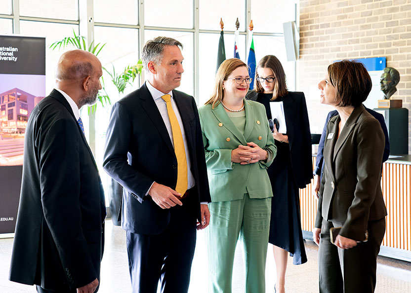 Four people standing in a sunny foyer having a conversation.