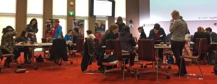 Men and women, informally sitting and standing in groups around tables, in discussions