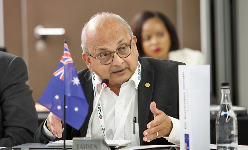 Man representing Australia, shown by a small Australian flag, speaking earnestly into a microphone