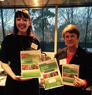 Two smiling women holding the 'among the gumtrees' booklets