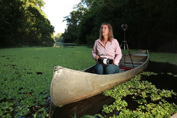 Kerrie Mengersen in a canoe on a river, holding a VR headset