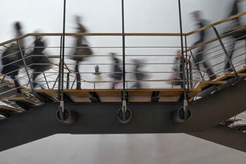 People cross the landing of a staircase at a university