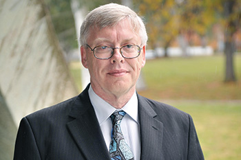 Dr Graeme Moad stands outside smiling at the camera