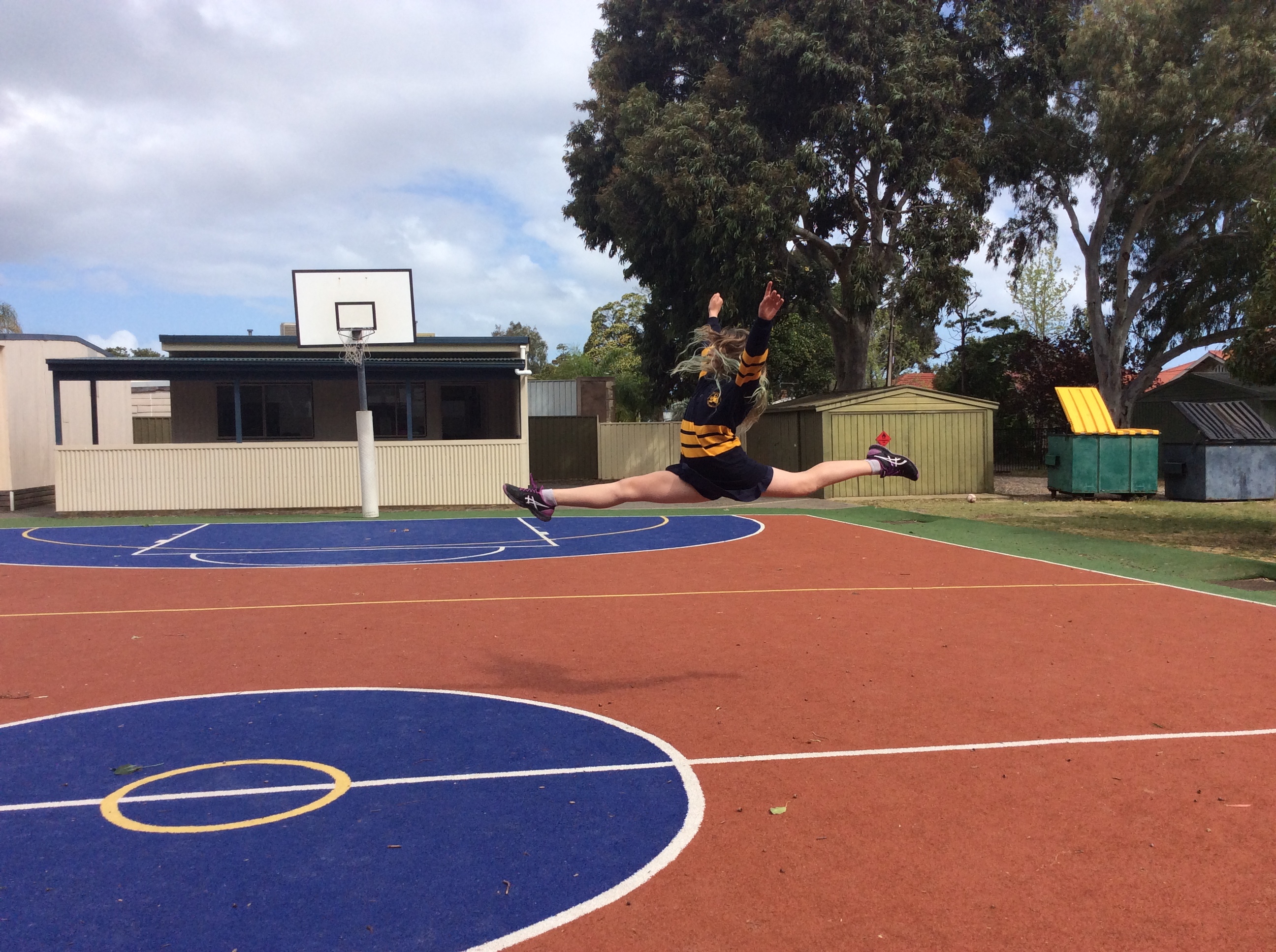 Name: Maddison. Prize: Shortlist. This is a photo of a leap, as you can see my legs are at an 180° angle this means that my legs have made a straight angle. My arms have made an acute angle. The bins in the background have made a 70° angle with their lids.